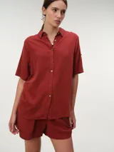 Camisa de manga corta color verde oliva, con cuello camisero, cierre frontal con botones y diseño fluido y relajado.