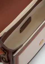 Bolso bandolera de diseño estructurado con cuerpo de tejido efecto rafia en color beige y detalles de ribetes y correa en cuero sintético color marrón. Presenta una solapa frontal con cierre de hebilla decorativa y botón magnético, y una correa larga ajustable para llevar al hombro o cruzado.