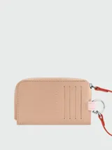 Tarjetero Longchamp Le Pliage Baroudeur de cuero color tostado, con cierre de cremallera, ranuras para tarjetas en el exterior y anilla metálica con detalles en rosa y tiras rojas.