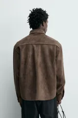 Sobrecamisa de corte regular fit confeccionada en tejido con efecto ante. Presenta cuello solapa, cierre frontal con botones a presión, mangas largas con puños abotonados y dos bolsillos de plastrón con solapa en el pecho.