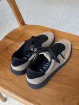 Championes urbanos con diseño de estampado animal print tipo vaca, confeccionados en cuero con textura de pelo. Presentan cordones marrones, suela de goma en tono tostado y detalles en color marrón oscuro en el cuello y lengüeta.