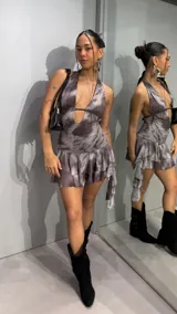 Vestido corto con diseño tie-dye en tonos marrones y grises, escote halter pronunciado con tiras finas cruzadas en el pecho, espalda descubierta y falda con volados en capas.