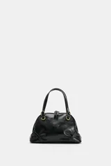 Bolso mini tipo bandolera de cuero sintético negro con acabado brillante, asas de mano y herrajes metálicos dorados. Cuenta con cierre de cremallera superior y detalles fruncidos en la base.