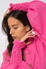 Camisa oversize color fucsia, de lino, con cuello camisero, cierre frontal con botones y mangas largas abullonadas con puños elásticos.