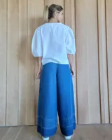 Pantalón de jean azul de corte palazzo con cintura alta y detalle de costuras horizontales en el ruedo.