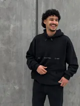 Canguro negro con capucha ajustable con cordones, bolsillo tipo canguro y estampado frontal con el texto "Crafted Project" y símbolos gráficos.