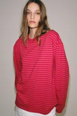 Remera de manga larga con diseño de rayas horizontales en tonos fucsia y rosado, cuello redondo y corte holgado.
