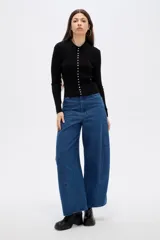 Remera de manga larga ajustada al cuerpo, confeccionada en tejido acanalado de color negro. Presenta cuello tipo polo y cierre frontal con una hilera de botones pequeños.