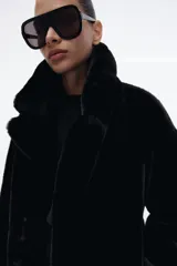 Abrigo de Zara con efecto pelo, cuello de solapa con muescas, manga larga y bolsillos delanteros. Cuenta con forro interior a tono y cierre frontal mediante ganchos metálicos.