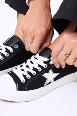 Championes de lona color negro con puntera y cordones blancos, presentan un detalle de estrella blanca en el lateral.