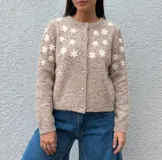 Cardigan de punto color blanco con diseño de flores bordadas en tono beige, cuello redondo, cierre frontal con botones forrados y mangas largas con puños acanalados.