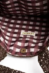Bolso tipo shopper tejido de papel con diseño de rayas verticales en tonos marrón, celeste, verde oliva y beige. Cuenta con doble asa de hombro y detalle de etiqueta de marca en el frente.