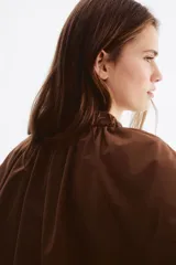 Campera bomber oversized color marrón con cuello elevado fruncido, cierre frontal y mangas raglán con puños elásticos.