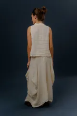 Pollera larga de lino color gris topo, de diseño amplio con volumen, movimiento y bolsillos delanteros. Cuenta con elástico en la cintura y detalles de pinzas y sobretelas en los laterales.