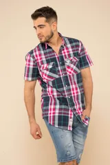 Camisa de manga corta con estampado de cuadros en tonos fucsia, azul marino, verde y blanco. Presenta cuello clásico, cierre frontal con botones y dos bolsillos delanteros con solapa en el pecho.