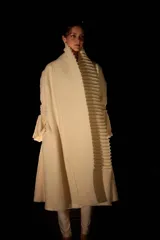 Tapado largo color crudo, confeccionado en lana merino afieltrada. Presenta cuello alto y guarda tejida en el cuello y ruedo. Tiene un estampado de una luna en la espalda.