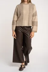 Sweater de tejido de punto grueso, con diseño de rayas verticales anchas en tonos marrón oscuro y negro. Presenta cuello redondo y mangas largas.