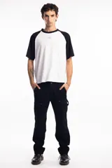 Remera de corte oversize con diseño tipo ranglan, que combina cuerpo blanco con mangas y cuello en color negro. Presenta un pequeño logo bordado en el centro del pecho.