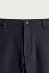 Pantalón de corte slim fit y color negro, confeccionado en tejido elástico. Cuenta con cintura elástica, trabillas, bolsillos frontales y cierre con cremallera y botón.