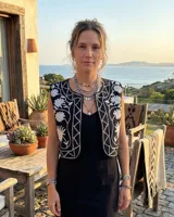 Chaleco negro de algodón con bordados florales en blanco, de corte cropped y sin mangas.