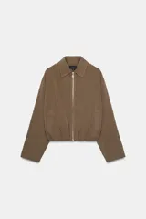 Cazadora tipo bomber color marrón, confeccionada en mezcla de viscosa. Tiene cuello solapa, manga larga, bolsillos de vivo en los laterales y bajo acabado en elástico. Cierre frontal con cremallera metálica.