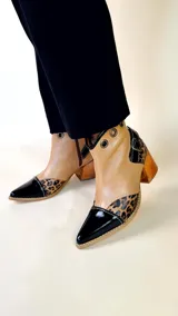 Bota tejana de cuero, combinada en color tostado, animal print de leopardo y puntera en charol negro. Cuenta con taco de madera, detalle de hebilla lateral y ojales metálicos en la parte superior.