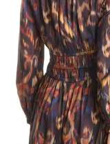 Vestido midi de manga larga con escote en V, confeccionado en tela fluida con estampado abstracto multicolor. Presenta una cintura elástica fruncida que define la silueta y una falda con caída suave y movimiento.