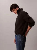 Buzo polar Calvin Klein de textura suave, con cuello alto y cierre de media cremallera frontal. Presenta un diseño de manga larga con corte regular y logo de la marca sutilmente bordado en el pecho.