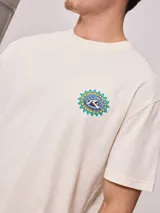 Remera color crema de corte holgado con estampado circular en el pecho.