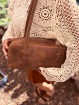 Cartera baguette de cuero color marrón con forro interno de tela.