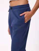 Pantalón tipo babucha de algodón y poliéster, con cintura elástica ajustable mediante cordón, bolsillos laterales y puños elásticos en los tobillos. Presenta un pequeño logo bordado en la pierna izquierda.