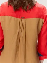 Camisa de lino color blanco con detalles combinados en tonos beige, cuello camisero, cierre frontal con botones oscuros y mangas largas con puños en contraste.