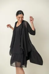 Vestido negro de seda, modelo suelto sin mangas, con escote redondo y volados en el bajo.