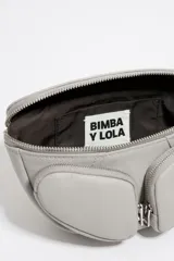 Riñonera de cuero gris con diseño de bolsillos frontales con cierre, correa de cuero ajustable y detalle de cadena metálica decorativa. Cuenta con cierre principal de cremallera y logo estampado en la parte superior.