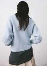 Sweater de punto celeste con cuello polo y cierre frontal en V, manga larga con puños ajustados y diseño acanalado.