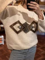 Sweater negro de tejido flexible con apliques geométricos metálicos bordados a mano.