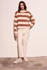 Pantalón de jean color crudo, corte flare, tiro medio y detalle de tachas plateadas en los laterales.