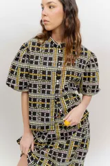 Camisa de popelina de algodón con cuello mao, botones frontales agrupados en pares y mangas cortas abullonadas tipo balloon. Cuenta con un diseño estampado de patrón geométrico y floral sobre fondo negro.