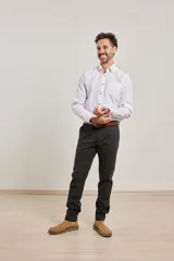 Pantalón de vestir verde oliva, de corte slim fit, sin pinzas, con bolsillos laterales y traseros. Se ajusta a la cintura con cinturón de cuero marrón.