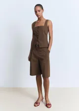 Chaleco de corte recto y diseño sin mangas, confeccionado en algodón. Presenta cuello escotado, cierre frontal con botones y dos bolsillos de ribete en la parte delantera.