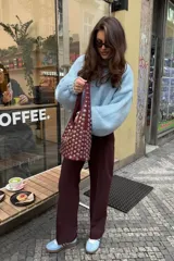 Bolso tipo tote de cuero sintético color borgoña, con apliques metálicos plateados y asa corta.