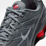 Championes Nike Shox Ride 2 en color gris humo, con tecnología de amortiguación Shox en el talón en color rojo vibrante. Presenta una parte superior de malla transpirable con superposiciones sintéticas y el logo Swoosh en el lateral.