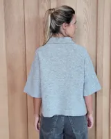 Cardigan de punto color arena, con cuello camisero, cierre frontal de botones y mangas cortas con terminación acanalada. Presenta dos bolsillos frontales tipo parche.