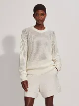 Sweater de punto calado color crema, de corte holgado y cuello redondo.