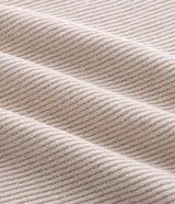 Remera de manga larga estilo Henley, confeccionada en tejido texturizado color beige, con cuello redondo y cierre frontal parcial de botones.
