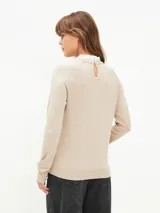 Buzo de tejido fino color beige, con cuello redondo y mangas largas con puños acanalados.