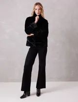 Chaqueta de piel sintética de alta densidad, con silueta recta, cuello alto envolvente y cierre frontal oculto. Cuenta con bolsillos laterales y forro interno a tono.