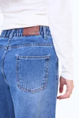 Jean de corte wide leg en color azul medio con efecto lavado. Presenta tiro medio, cierre frontal con botón y bolsillos laterales y traseros.