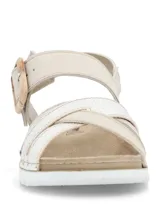 Sandalias planas de mujer en color beige, con tiras cruzadas en el empeine, una de ellas con textura plateada brilhante. Cuenta con tira ajustable al tobillo mediante hebilla con efecto carey y suela blanca con base dentada.