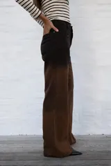 Jean de mujer de corte recto y tiro alto, con efecto degradado de negro a marrón. Presenta costuras verticales en la parte delantera y bolsillos laterales.